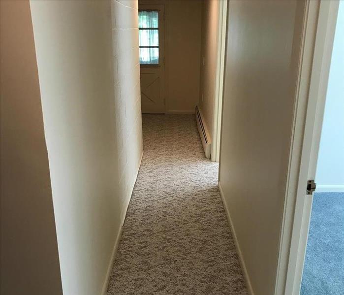 The hallway has been repaired and has new carpets after a flood.