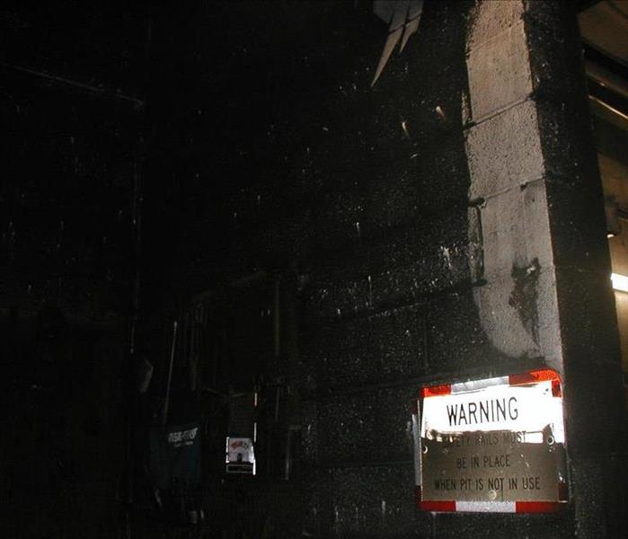 A manufacturing company's workroom is covered in soot after a fire.