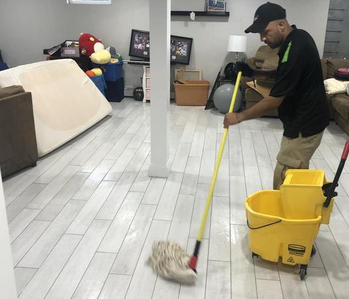 SERVPRO technician removes standing water from a basement floor.