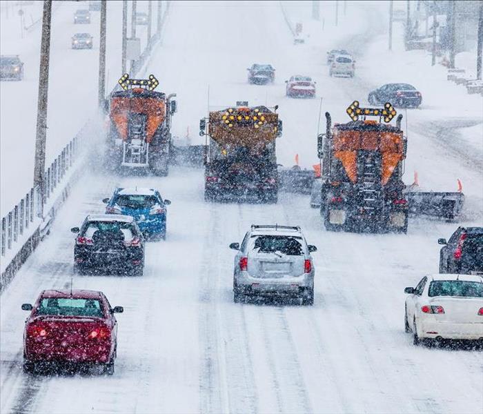Cars driving on a highway in a snow storm.